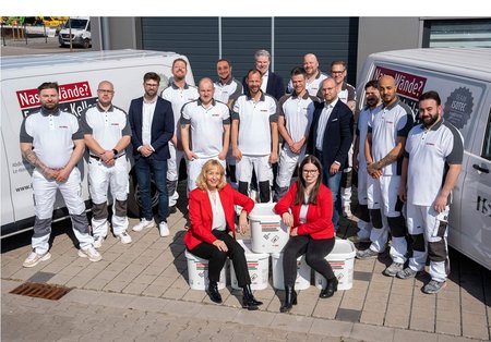 ISOTEC Team posiert draußen vor Firmenfahrzeugen